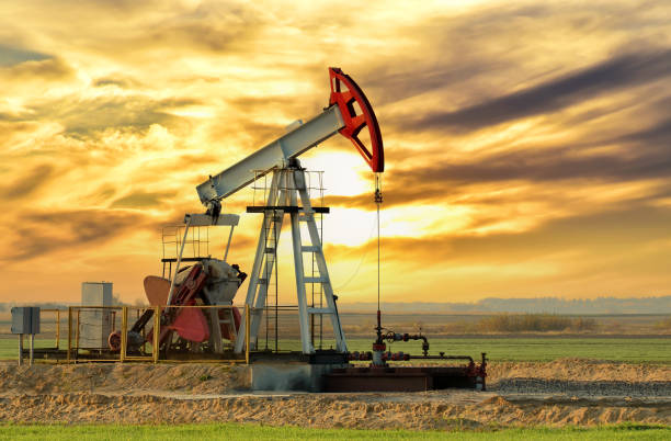 Crude oil pump jack at oilfield on sunset backround. Fossil crude output and fuels oil production. Oil drill rig stock photo