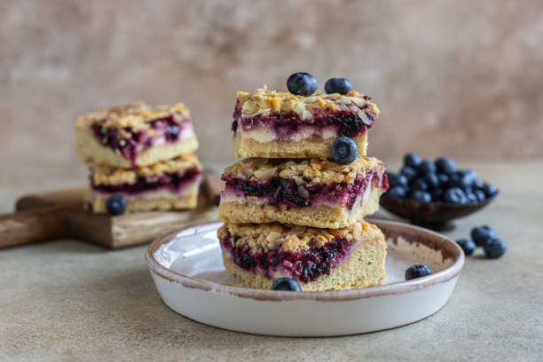 Crumble cheesecake bars with blueberry filling and fresh blueberries, concrete background. Bar slices with cheesecake, blueberry and streusel. stock photo