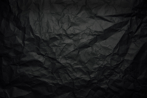 Close-up of crumpled black rice paper background with spotlight.
