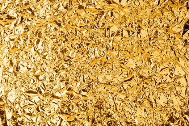 Crumpled golden foil shining texture background, bright shiny gold luxury design, metallic glitter surface, holiday decoration backdrop concept, gold metal shimmer effect, sparkling yellow pattern stock photo