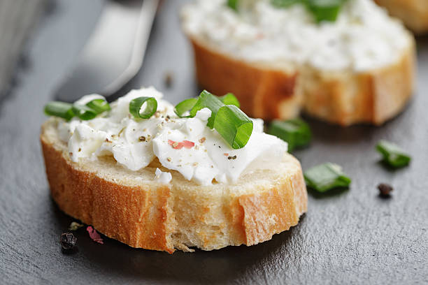 crunchy baguette slices with cream cheese and green onion crunchy baguette slices with cream cheese and green onion on slate board, shallow focus crostini photos stock pictures, royalty-free photos & images