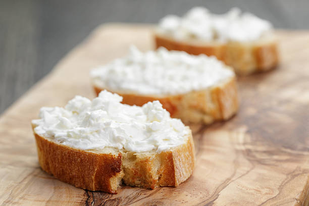 crunchy baguette slices with cream cheese on olive board crunchy baguette slices with cream cheese on olive board, shallow focus crostini photos stock pictures, royalty-free photos & images