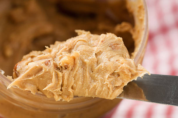 Crunchy Peanut Butter A heap of crunchy peanut butter on a knife coming out of the jar. crunchy stock pictures, royalty-free photos & images