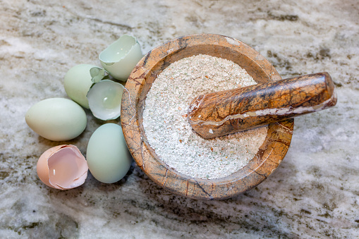 Blue and brown chicken eggs crushed by a mortar and pestle.