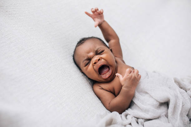 weinend und verärgert und wütend afroamerikanische neugeborene junge auf einer cremedecke liegend - yelling stock-fotos und bilder