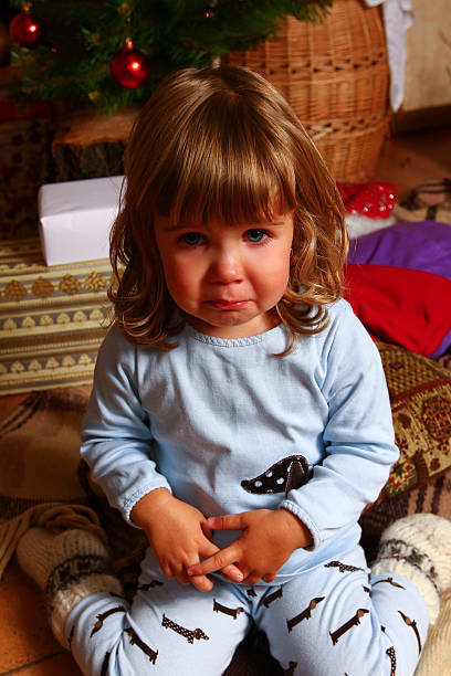 Crying baby near Christmas tree stock photo