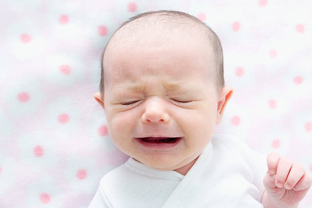 Crying baby on pink blanket stock photo