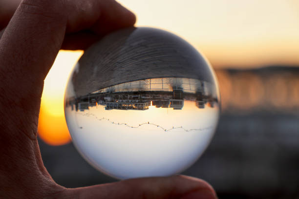Crystal ball wih recletion of Limassol´s harbour at sunset. Glass/Lens ball holding in hand with golden city lights and sea in the background reflecting the city of Limassol at sunset. Cyprus stock photo