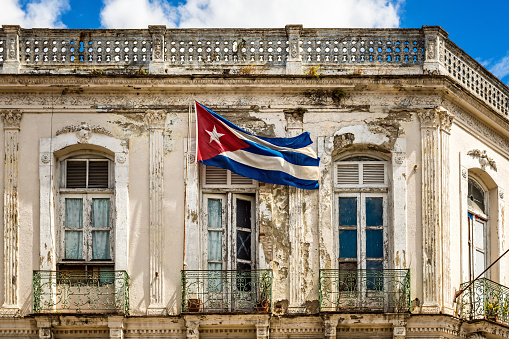 Cuban national flag on pole set on balcony of obsolete building in Santa Clara, Cuba. Taken by Sony a7R II, 42 Mpix.