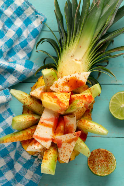 pepino, jícama y piña con chile en polvo y salsa chamoy sobre fondo turquesa. merienda mexicana - fruta con chamoy fotografías e imágenes de stock