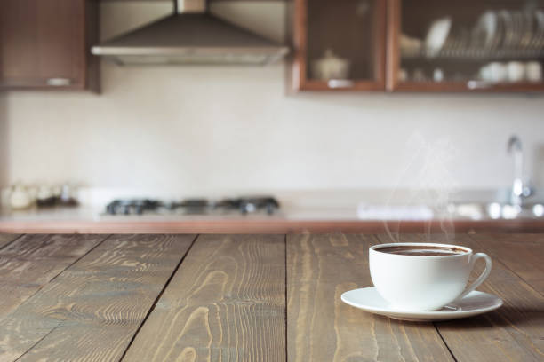 Cup of black coffee on wooden tabletop in blurred modern kitchen. Close up. Indoor. Cup of black coffee on wooden tabletop in blurred modern kitchen. Close up. Indoors. morning cup of coffee stock pictures, royalty-free photos & images