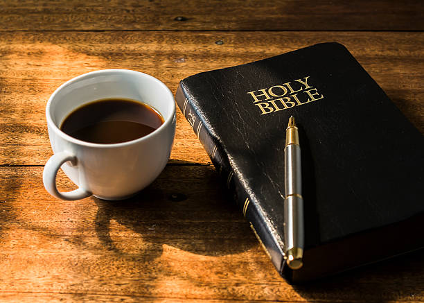 Cup of coffee and holy bible on wooden table stock photo