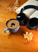 istock A cup of coffee , wireless headphones and a book on a wooden table with autumn maple leaves. Home workplace, Audi book concept 1338722858
