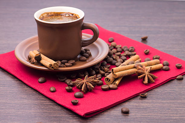 Cup of Coffee with Beans and Spices on Red Napkin