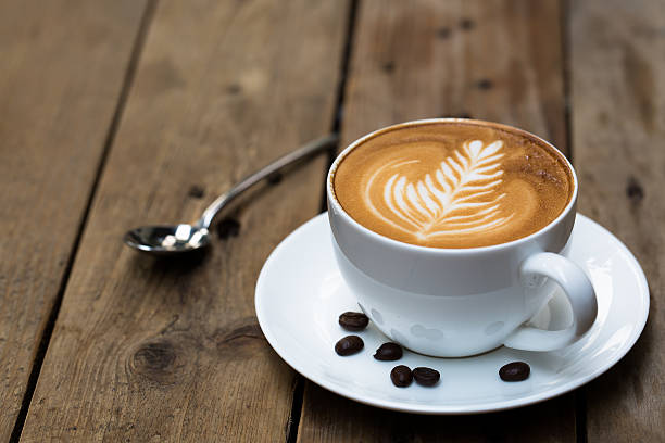 cup of hot latte art coffee on wooden table - cappuccino stockfoto's en -beelden