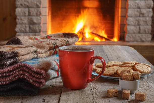 Cup of tea and sugar,  woolen things near  cozy fireplace. stock photo