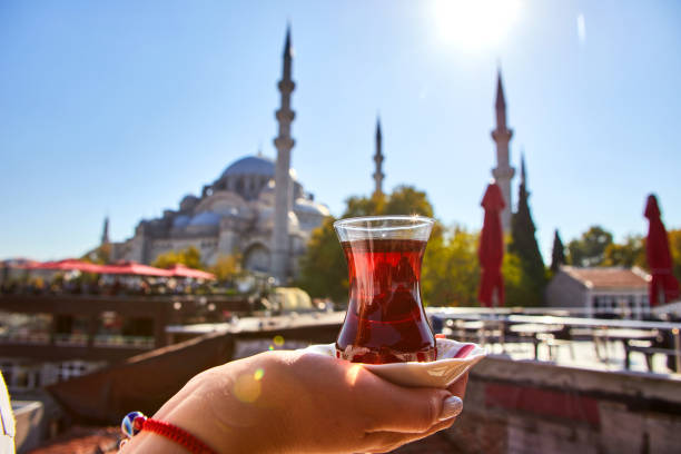 A cup (armud) of traditional Turkish tea in hand against the background of a mosque in Istanbul stock photo