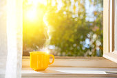 Good morning! Cup on the window with sun and defocused nature background