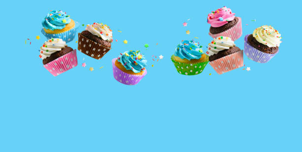 Cupcakes with pink white and blue cream and colorful sprinkles flying over blue background. Copy space Delicious Cupcakes for party, birthday. Various cupcakes with pink white and blue cream flying over blue background cupcake stock pictures, royalty-free photos & images