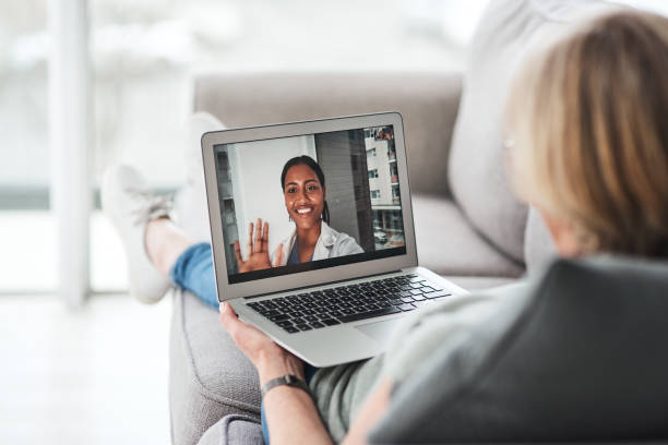 Curb the spread, have your checkup at home instead Shot of a senior woman using a laptop to make a video call with her doctor on the sofa a home telemedicine stock pictures, royalty-free photos & images