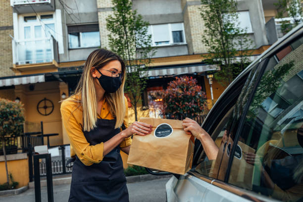 Curbside pick up restaurant worker giving order bags to customer Man picking restaurant food from car at a Curbside pickup curbsidepickup stock pictures, royalty-free photos & images