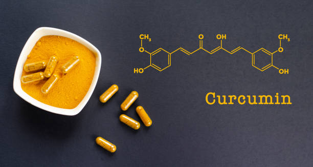 Curcumin formula with yellow turmeric root powder and capsules stock photo