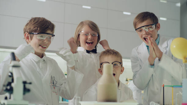 Curious boys conducting science experiment. Laboratory interior, seething, foamy liquid. Celebrating success stock photo