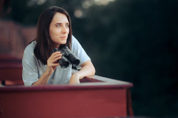 Curious Woman Holding a Pair of Binocular Spying on her Neighbors stock photo