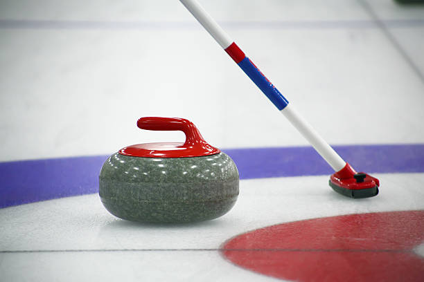 Curling stone and broom on the ice stock photo