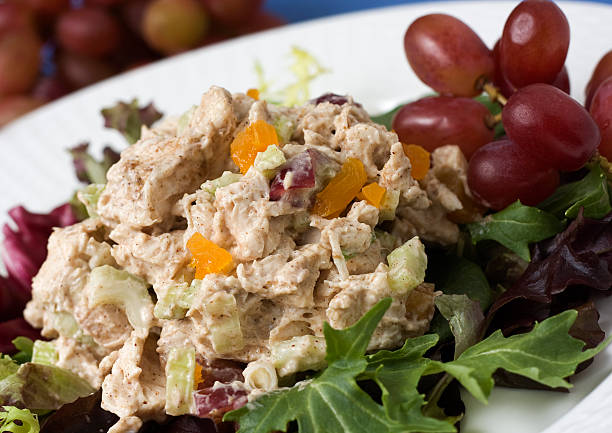 Curried Chicken Salad Curried spiced chicken salad with dried apricots and grapes, served on a bed of lettuce. chicken salad stock pictures, royalty-free photos & images