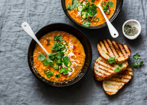 Curried red lentil tomato and coconut soup - delicious vegetarian food on grey background, top view. Flat lay served healthy lunch stock photo