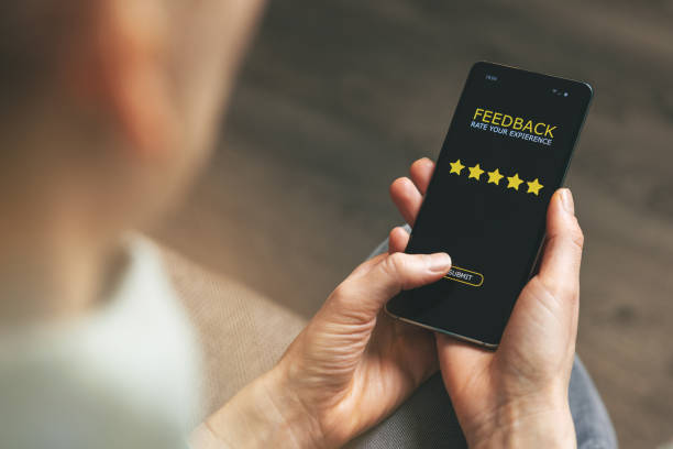 customer feedback - woman using phone to give 5 star rating for good service stock photo