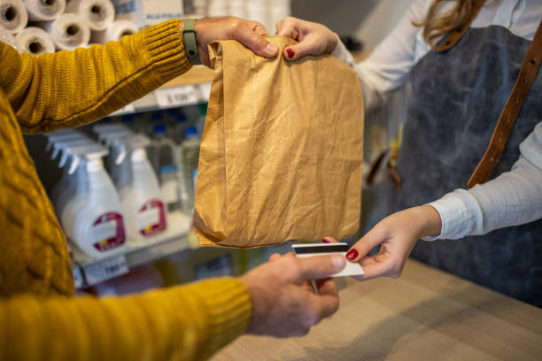 customer giving his credit card to a saleswoman - trouwpak stockfoto's en -beelden