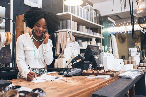 Customer service is her speciality Shot of a happy young shopkeeper using her cellphone while standing behind the counter in her shop entrepreneur stock pictures, royalty-free photos & images