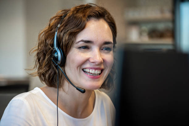 Customer service representative wearing headset in the office Smiling mature female customer service representative wearing headset while working in office call center photos stock pictures, royalty-free photos & images
