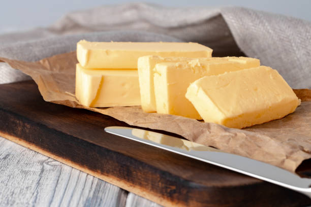 snijd boter op plaat met blauwe handdoek op keukenlijst - boter stockfoto's en -beelden