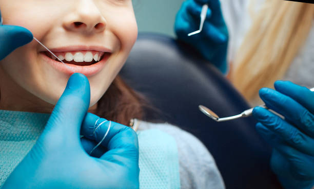 Cut view hands in latex gloves to floss child front teeth. Woman hold dental tools beside. stock photo