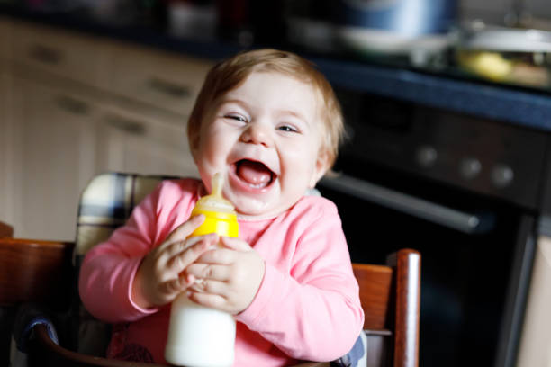 urocza urocza dziewczynka z ewborn trzymająca butelkę pielęgniarską i pijącą mleko z formułą - baby formula zdjęcia i obrazy z banku zdjęć