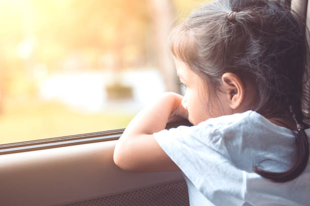 Cute asian little child girl sitting in the car and look out from the car window Cute asian little child girl sitting in the car and look out from the car window in the sunset cute thai girl stock pictures, royalty-free photos & images