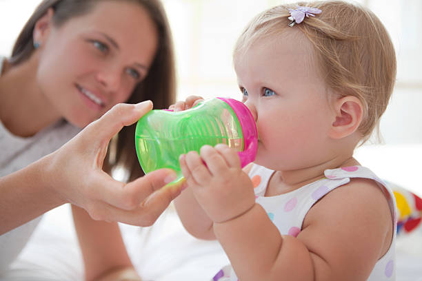 Cute baby drinking water. Smiling mother helping her cute baby drink water from sippy cup.See more LIFESTYLE and MEDICAL images with this cute BABY an her MOTHER. Click on image below for lightbox. cold drink photos stock pictures, royalty-free photos & images