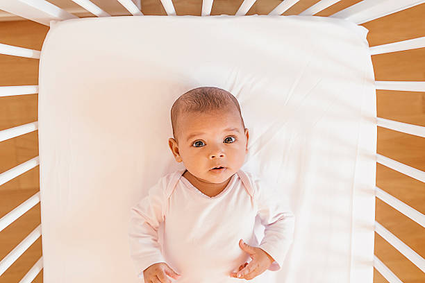 cute baby girl lying in the crib - cradle to cradle stockfoto's en -beelden