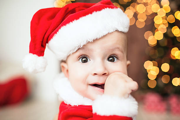 Cute baby in santa suit near xmas tree stock photo