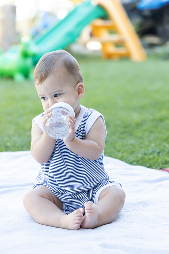 Cute Baby sitting in the yard at home drinking