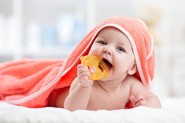 Cute baby with teether under a hooded towel after bath stock photo