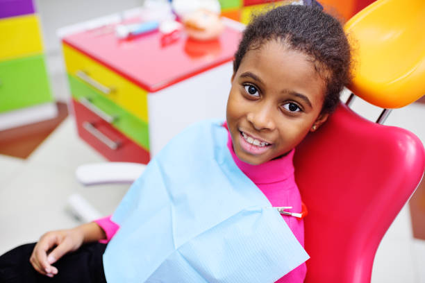 cute black baby girl smiling sitting in a red dental chair cute black baby girl smiling sitting in a red dental chair at the examination at the children's dentist rotten teeth in children stock pictures, royalty-free photos & images