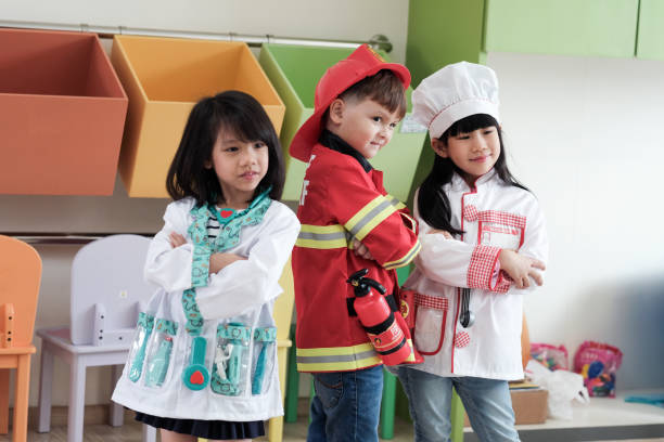 Cute boy and girls playing as fireman, doctor and cook occupation in kindergarten class, kid occupation, education concept Cute boy and girls playing as fireman, doctor and cook occupation in kindergarten class, kid occupation, education concept dressing up stock pictures, royalty-free photos & images
