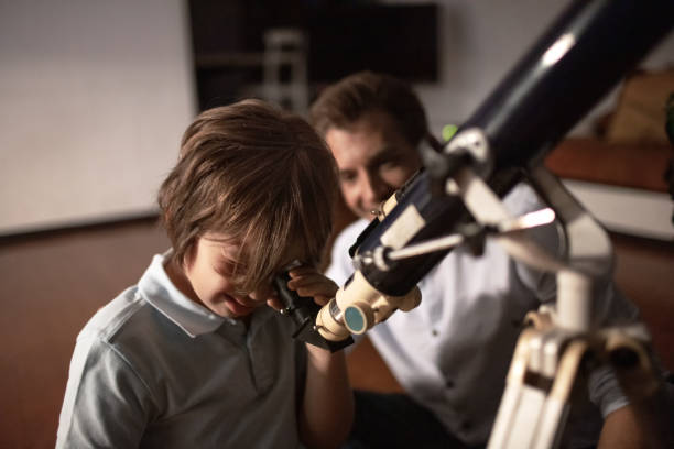 Cute Boy looking At Sky Through Telescope With His Father Cute boy looking at sky through telescope with his father. astronomy telescope stock pictures, royalty-free photos & images