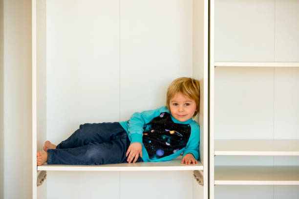 Cute child, sit in a white box in open wardrope stock photo