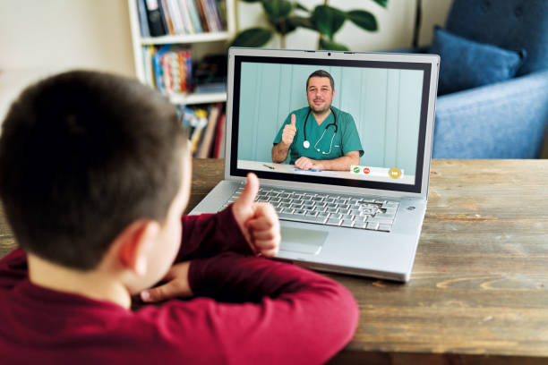 Cute child talking with doctor on video call. There is good news from doctor. Family is happy. Cute child talking with doctor on video call. There is good news from doctor. Family is happy. nurse talking to camera stock pictures, royalty-free photos & images
