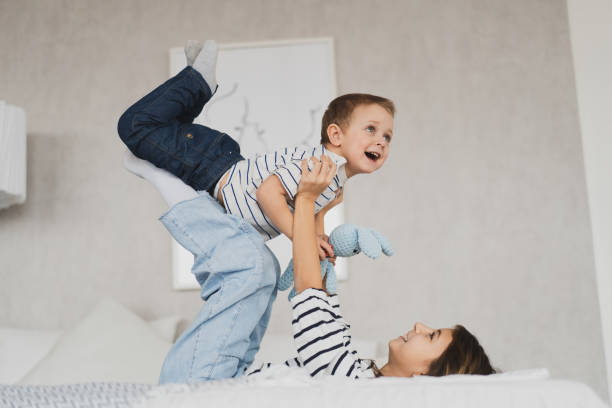 cute children, brother and sister have fun on the bed at home stock photo
